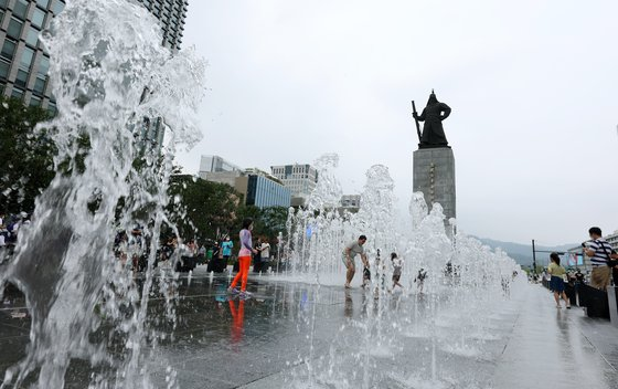서울 광화문광장 이순신 장군 동상 앞 명량분수대에서 아이들이 더위를 식히고 있다.[뉴스1]